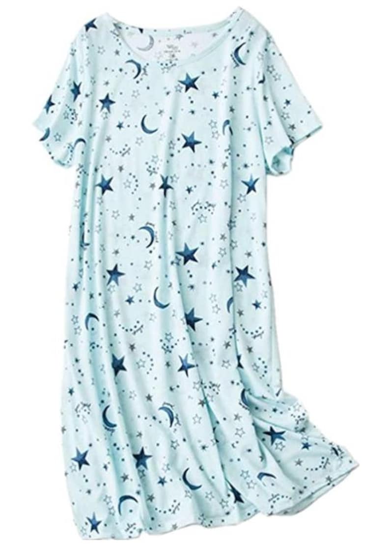 May include: A light blue nightgown featuring a celestial pattern of navy blue stars, crescent moons, and smaller star clusters. The short-sleeved sleep dress is made of a soft, flowing fabric.