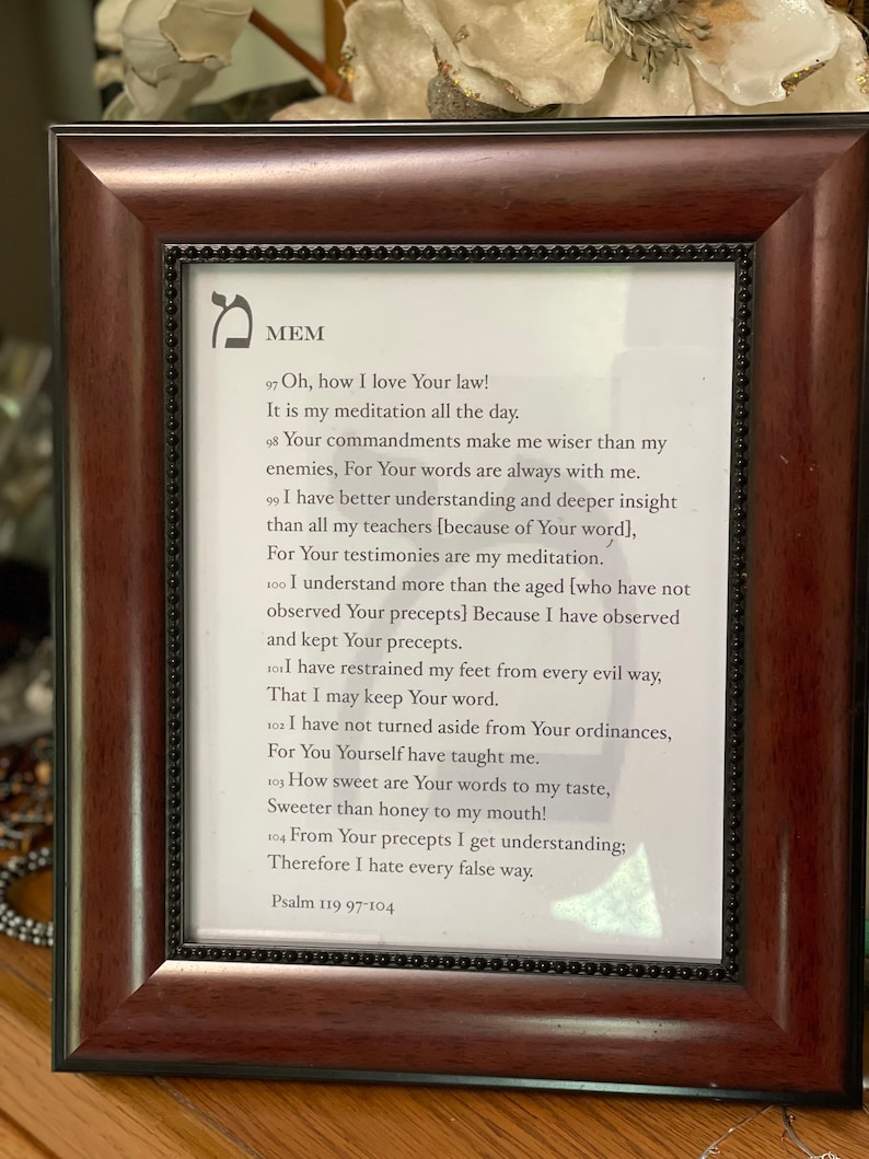 May include: A framed print of a religious passage from Psalm 119:97-104. The passage is written in English and Hebrew. The frame is brown wood with a black mat.