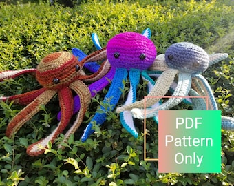 May include: Three crocheted octopus plushies in different colors: brown and orange, purple, and blue and green. The plushies are sitting on a bed of green foliage. The text "PDF Pattern Only" is visible in the image.