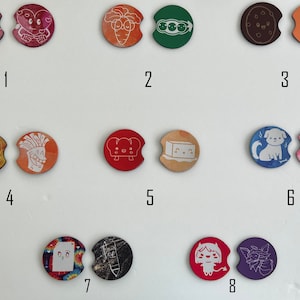 May include: Set of eight colorful round coasters with various designs. The coasters feature a variety of images, including a brain, a heart, a carrot, peas, a cookie, a milk carton, a hamburger, a mushroom, a slice of bread, a block of tofu, a dog, a cat, a tie-dye pattern, and a pencil. The coasters are numbered 1 through 8.