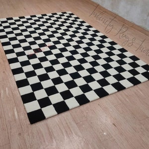 Pode incluir: Tapete xadrez preto e branco com um padrão quadrado. O tapete é feito de um material macio e felpudo e é perfeito para adicionar um toque de estilo moderno a qualquer cômodo.