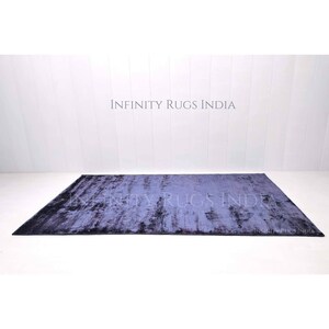 May include: A dark blue rug with a distressed, textured look. The rug has a subtle ombre effect, fading from a darker blue at the edges to a lighter blue in the center. The rug is made of a soft, plush material and is perfect for adding a touch of sophistication to any room.