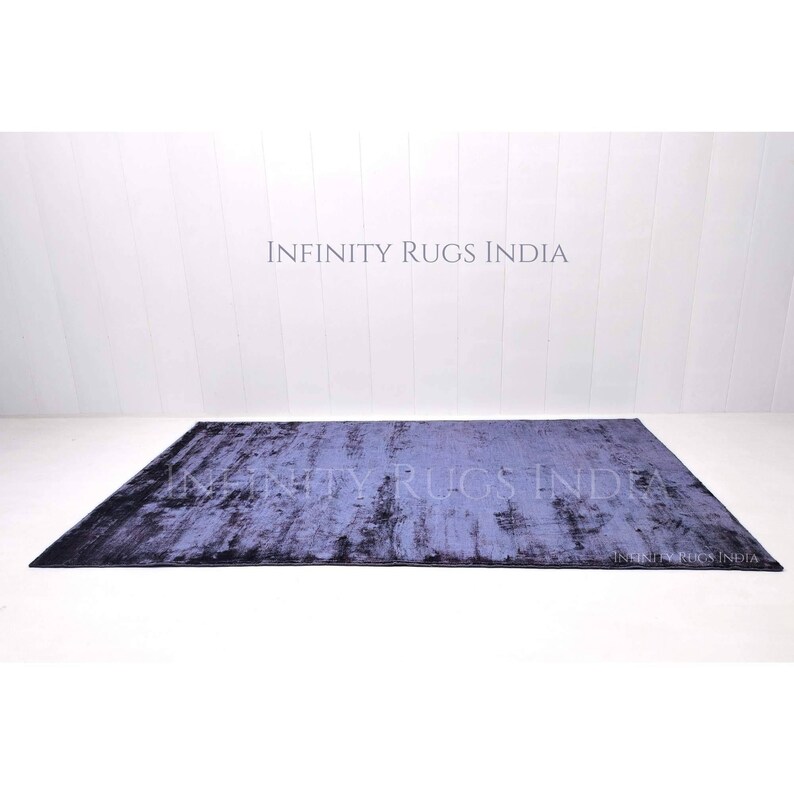 May include: A dark blue rug with a distressed, textured look. The rug has a subtle ombre effect, fading from a darker blue at the edges to a lighter blue in the center. The rug is made of a soft, plush material and is perfect for adding a touch of sophistication to any room.