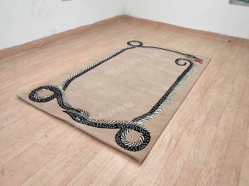 Może przedstawiać: Beżowy dywan z czarno-białym wzorem węża wzdłuż krawędzi. Dywan ma nadrukowany napis "Infinity Rugs India".