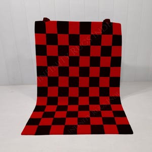 Pode incluir: Um tapete xadrez vermelho e preto com o texto "INFINITY RUGS INDIA" impresso nele.