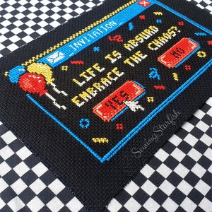 Pode incluir: Padr&atilde;o de ponto cruz de uma tela de computador com o texto "Life is hard, embrace the chaos." com um bot&atilde;o vermelho que diz "Sim" e um bot&atilde;o vermelho que diz "N&atilde;o".