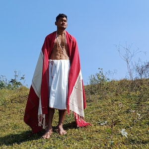 Peut inclure: Un homme portant une tenue traditionnelle indienne blanche et rouge, debout dans un champ herbeux avec un ciel bleu en arrière-plan.