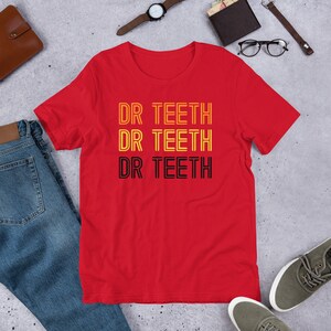 May include: Red t-shirt with the text "DR TEETH" repeated three times in a retro style with yellow and black outlines.