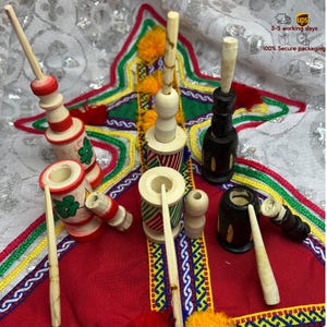 Puede incluir: Un conjunto de seis pipas para fumar de madera con diseños intrincados. Las pipas están pintadas en rojo, blanco, verde y negro. Cada pipa tiene una larga y delgada varilla de madera y un pequeño cuenco. Las pipas están dispuestas sobre una tela estampada en rojo y blanco.