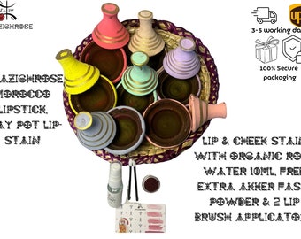 May include: A set of seven colorful Moroccan clay pots with gold accents, arranged in a woven basket. The pots are filled with a dark brown substance. The set includes a small bottle of liquid, a small container of powder, and two lip brush applicators.  Lip & Cheek Stain with Organic Rose Water 10ml, Free Extra Akker Fassi Powder & 2 Lip Brush Applicators.