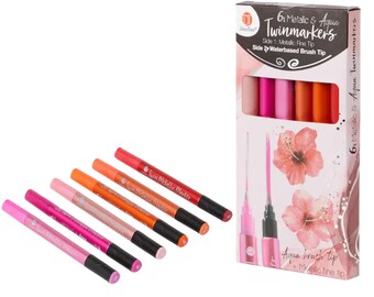 May include: A set of six metallic and aqua twin markers in shades of pink, orange, and red. The markers are displayed with their packaging, which features the text "6x Metallic & Aqua Twinmarkers". Each marker has a fine metallic tip on one end and a water-based brush tip on the other.