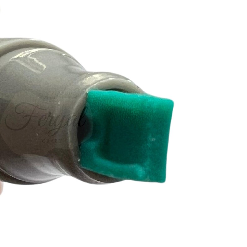 K&ouml;nnte beinhalten: Nahaufnahme eines grauen Markers mit einer quadratischen, smaragdgr&uuml;nen Filzspitze. Der K&ouml;rper des Markers ist in einem ged&auml;mpften Grauton gehalten, und die Spitze ist ein leuchtendes, sattes Gr&uuml;n. Das Bild ist vor einem wei&szlig;en Hintergrund.