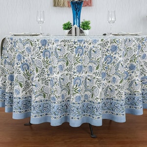 Round blue and white floral hand block printed cotton tablecloth, featuring intricate Indian design with green accents. Perfect dining table cover for farmhouse, cottagecore, or boho decor. Ideal for weddings, housewarming gifts, summer dining, or festive celebrations. Handmade by skilled artisans using traditional block printing techniques. Fits large round tables beautifully, adding elegance to your dining space.