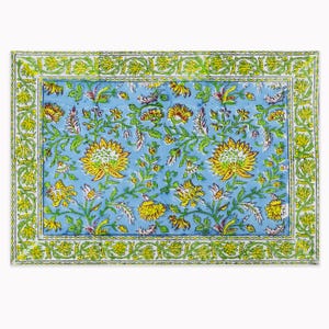 Op de afbeelding: Een rechthoekig textiel met een lichtblauwe achtergrond en een herhalend patroon van gele bloemen en groene ranken. Het ontwerp bevat een decoratieve rand met een doorlopend motief van groene ranken en gele bloemen.