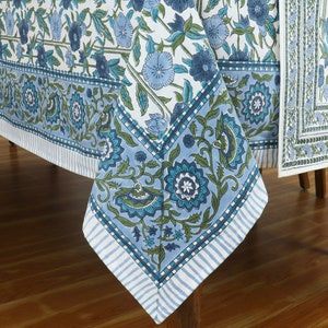 Puede incluir: Un mantel de mesa floral azul y blanco con un borde verde. El mantel está hecho de algodón y tiene un diseño tradicional indio.