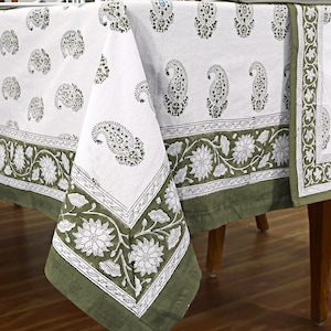 May include: White tablecloth with a green paisley and floral print border. The tablecloth is made of cotton and has a soft, natural feel.