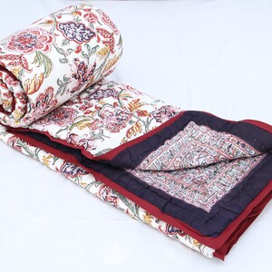 Op de afbeelding: Een wit katoenen dekbed met een bloemenprint in tinten rood, roze, geel en groen. Het dekbed heeft een bordeauxrode en donkerblauwe rand.