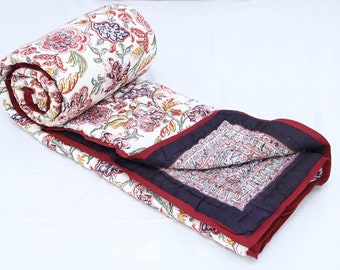 May include: A white cotton quilt with a floral print in shades of red, pink, yellow, and green. The quilt has a burgundy and navy blue border.