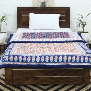 May include: A blue and white floral patterned quilt with a white pillow on a wooden bed frame. The quilt is folded back to reveal the floral pattern.