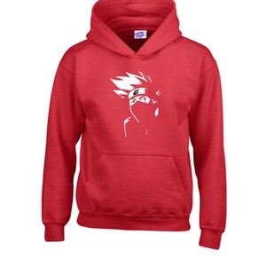 May include: A red hooded sweatshirt with a white graphic of a character from an anime series. The graphic is a stylized illustration of a person with spiky white hair, a headband, and a face covering. The sweatshirt has a kangaroo pocket.