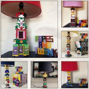 Puede incluir: Lámparas con bases construidas con bloques de juguete coloridos, con varios personajes de la cultura pop. Las pantallas de las lámparas son de diferentes colores. Las palabras "POPS AND TWINK" también están hechas con bloques de juguete.
