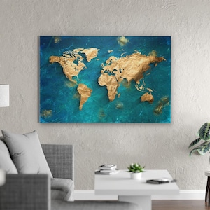 May include: A gold-coloured world map on a blue background. The continents are raised and textured, creating a 3D effect. The blue background resembles water, with gold accents. The artwork is rectangular and mounted on a wall.