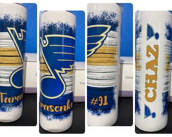 May include: Four white stainless steel tumblers with a blue and gold St. Louis Blues hockey team logo. The tumblers are personalized with the names "Tarasenko", "#91", and "CHAZ".