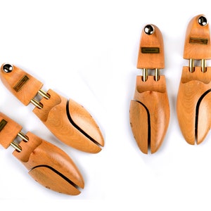 May include: Four wooden shoe trees with brass accents. The shoe trees are designed to help maintain the shape of shoes and prevent creases.
