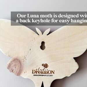 K&ouml;nnte beinhalten: Ein Wandbehang aus Holz in Form eines Luna-Nachtfalters mit einem Schl&uuml;sselloch auf der R&uuml;ckseite zum einfachen Aufh&auml;ngen. Der Falter ist hellbraun und hat eine nat&uuml;rliche Holzmaserung. Der Text "studi DreamON www.dreamon.STUDIO" ist auf der Unterseite des Falters aufgedruckt.