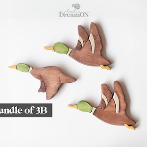 K&ouml;nnte beinhalten: Paket mit 3B Holz-Enten-Wanddekoration. Die Enten sind braun bemalt mit gr&uuml;nen K&ouml;pfen und gelben Akzenten. Sie fliegen in verschiedene Richtungen.