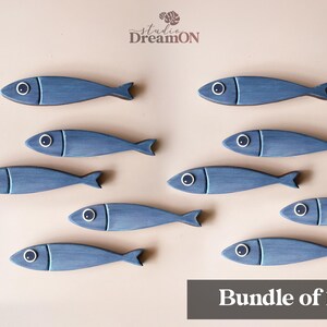 May include: Ten blue wooden fish decorations with white and black eye details are arranged on a light beige background. The fish have a rustic, hand-painted appearance. The text "Bundle of 10" is in a dark gray rectangle at the bottom.