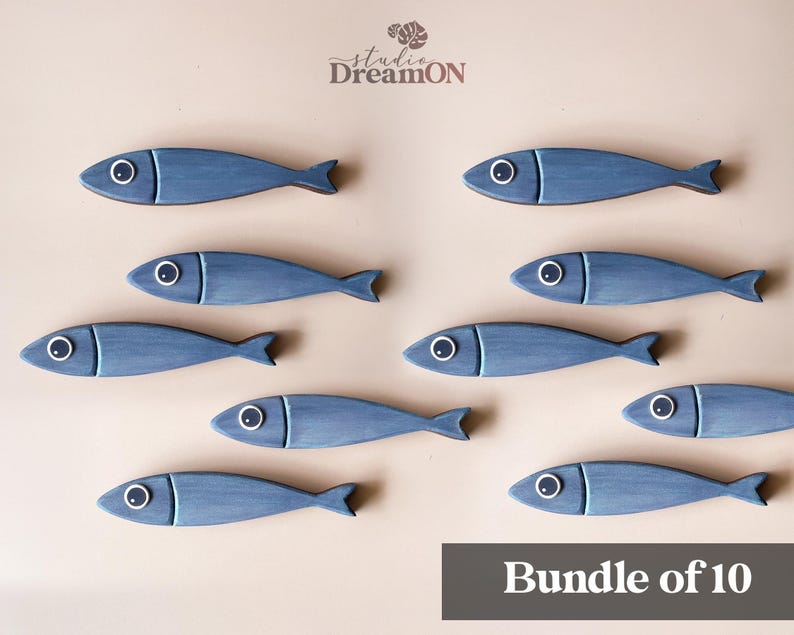 May include: Ten blue wooden fish decorations with white and black eye details are arranged on a light beige background. The fish have a rustic, hand-painted appearance. The text "Bundle of 10" is in a dark gray rectangle at the bottom.
