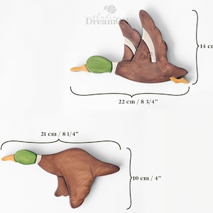 K&ouml;nnte beinhalten: Zwei h&ouml;lzerne Entenfiguren, eine fliegt und eine taucht, mit gr&uuml;nen K&ouml;pfen und braunen K&ouml;rpern. Die fliegende Ente ist 22 cm lang und 14 cm hoch. Die tauchende Ente ist 21 cm lang und 10 cm hoch.