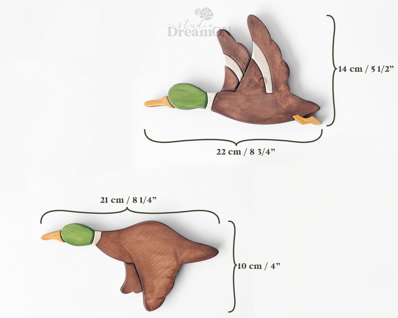 K&ouml;nnte beinhalten: Zwei h&ouml;lzerne Entenfiguren, eine fliegt und eine taucht, mit gr&uuml;nen K&ouml;pfen und braunen K&ouml;rpern. Die fliegende Ente ist 22 cm lang und 14 cm hoch. Die tauchende Ente ist 21 cm lang und 10 cm hoch.