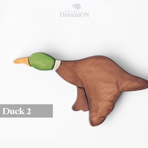 K&ouml;nnte beinhalten: Ein h&ouml;lzernes Entenspielzeug, das in Braun-, Gr&uuml;n- und Gelbt&ouml;nen bemalt ist. Die Ente ist im Flug mit ausgebreiteten Fl&uuml;geln. Das Spielzeug ist mit "Ente 2" beschriftet.
