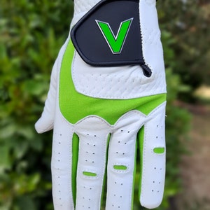 Op de afbeelding: Witte golfhandschoen met groene accenten en een zwarte patch met een groene "V" op de rug van de hand.