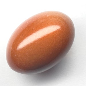 May include: A smooth, oval-shaped, brown object with a glossy finish. The object has a warm, earthy tone and reflects light, creating highlights. The shape is reminiscent of a polished stone or a large bead.