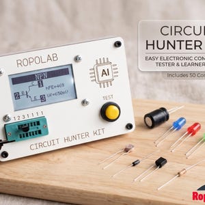 Op de afbeelding: Een witte Circuit Hunter Kit met een digitaal display met circuitinformatie. De kit bevat een testknop, een selectie van elektronische componenten en de tekst "CIRCUIT HUNTER KIT". De kit staat op een houten oppervlak.