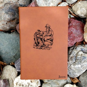 May include: A brown leather journal with a black and white illustration of a man panning for gold. The journal is personalized with the name "Jason".