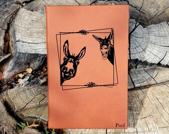 May include: A brown leather journal with a black donkey design and the name "Paul" engraved on the front.