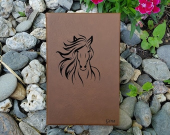 May include: Brown leather journal with a horse head design and the name "Gina" engraved on the bottom.