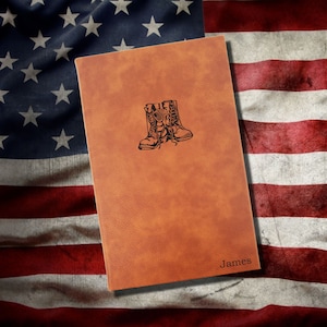 May include: A brown leather journal with a design of military boots and dog tags. The journal is personalized with the name "James".