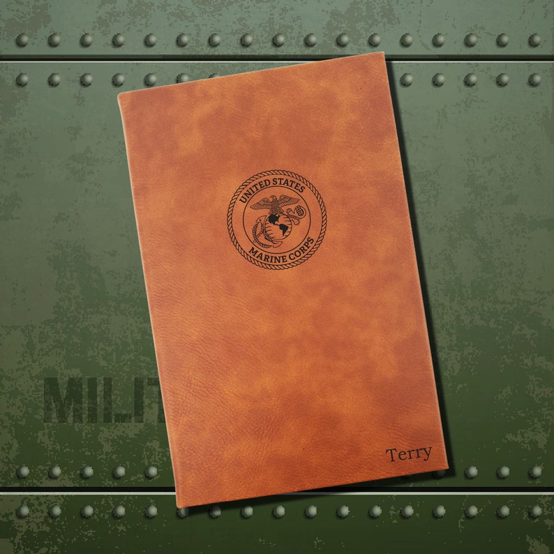May include: A brown leather journal with the United States Marine Corps emblem embossed on the front. The name "Terry" is engraved on the bottom right corner.