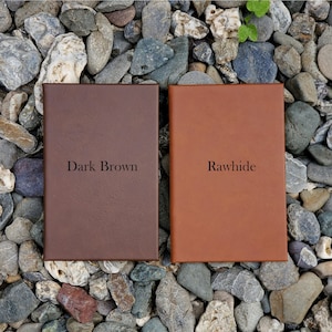 May include: Two leather-bound journals, one dark brown and one rawhide, with the color names printed on the front.