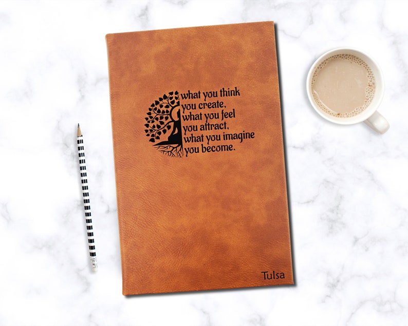 May include: Brown leather journal with a tree of life design and the quote "what you think you create, what you feel you attract, what you imagine you become." The journal is personalized with the name "Tulsa".