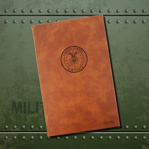 May include: A brown leather journal with the United States Air Force seal embossed on the front. The name "Sam" is embossed on the bottom right corner.