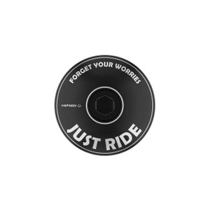 Peut inclure: Bouchon de jeu de direction de vélo noir avec les mots "FORGET YOUR WORRIES" et "JUST RIDE" en lettres blanches. Le bouchon comporte également le mot "caphappy" et un smiley. Un boulon hexagonal est au centre.