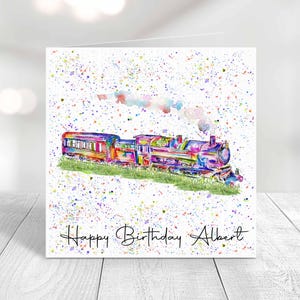 May include: A square greeting card featuring a watercolour illustration of a steam train in vibrant multi-coloured hues, set against a white background with colourful paint splatters and smoke. The text Happy Birthday Albert is written below.