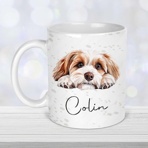 Peut inclure: Mug en céramique blanche avec une illustration de chien marron et blanc. Le nom du chien, "Colin", est écrit en cursive sous l'image. La tasse a une anse blanche et est décorée de petites mouchetures grises.