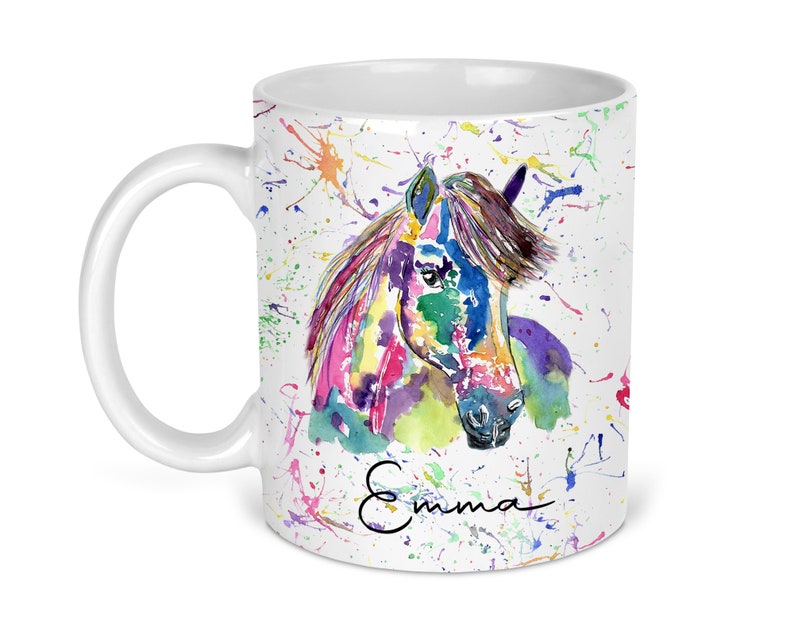 Puede incluir: Taza de cer&aacute;mica blanca con una pintura de acuarela colorida de la cabeza de un caballo. El fondo es blanco con salpicaduras de pintura de colores. El nombre "Emma" est&aacute; escrito en cursiva en la parte inferior de la taza.